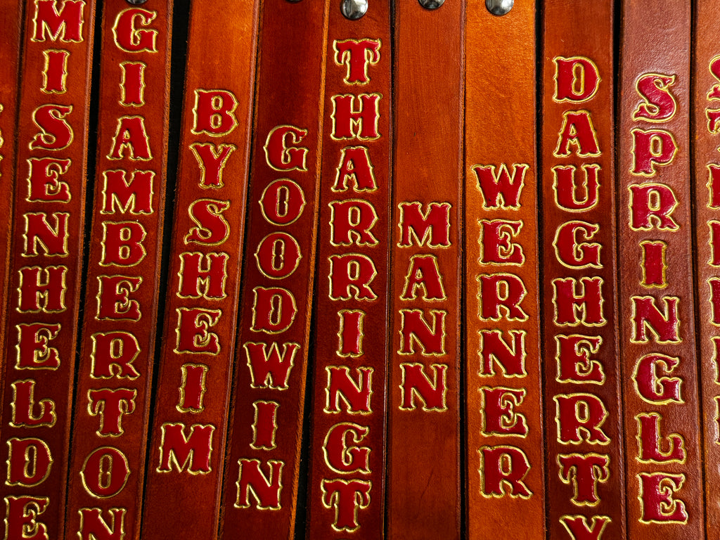 Row of extra-long custom leather SCBA quick release pulls with swivel snaps, personalized with firefighter names and units.