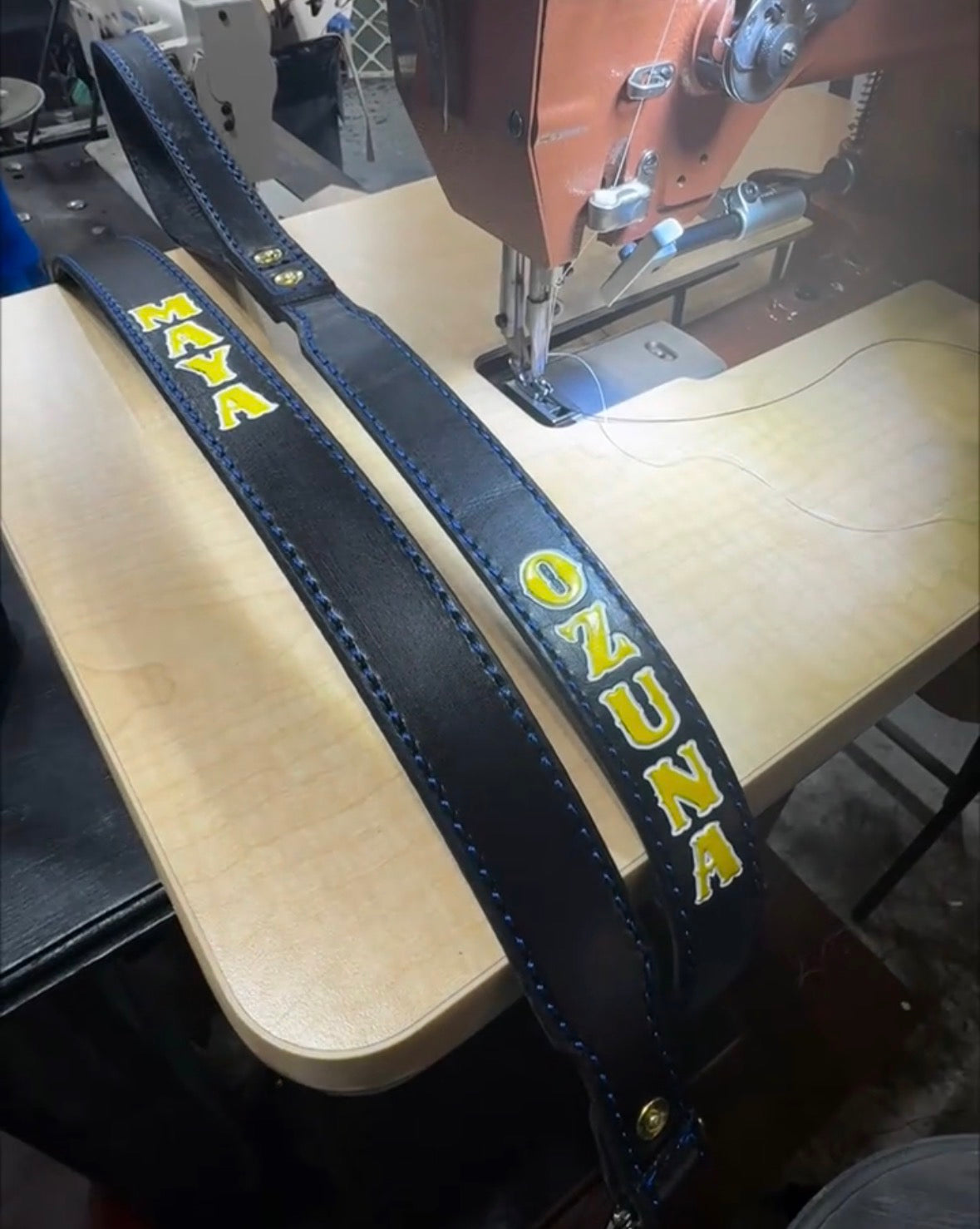Personalized black leather dog leash showing custom stamped names with hand-painted lettering during the handcrafted production process.