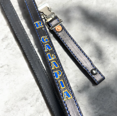 Personalized leather firefighter helmet chin strap with blue stitching and hand-painted name.
