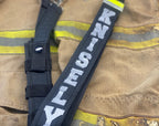 Close-up of personalized firefighter radio strap with silver reflective name mounted on firefighter turnout gear.