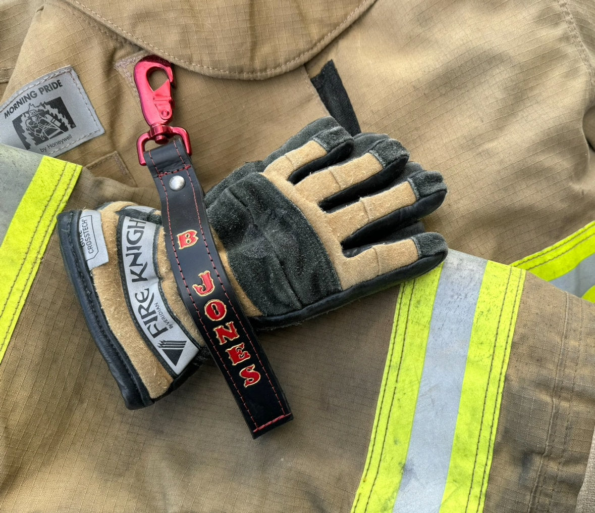 Close-up of personalized leather firefighter glove strap showing custom paint, stitching, and premium leather.