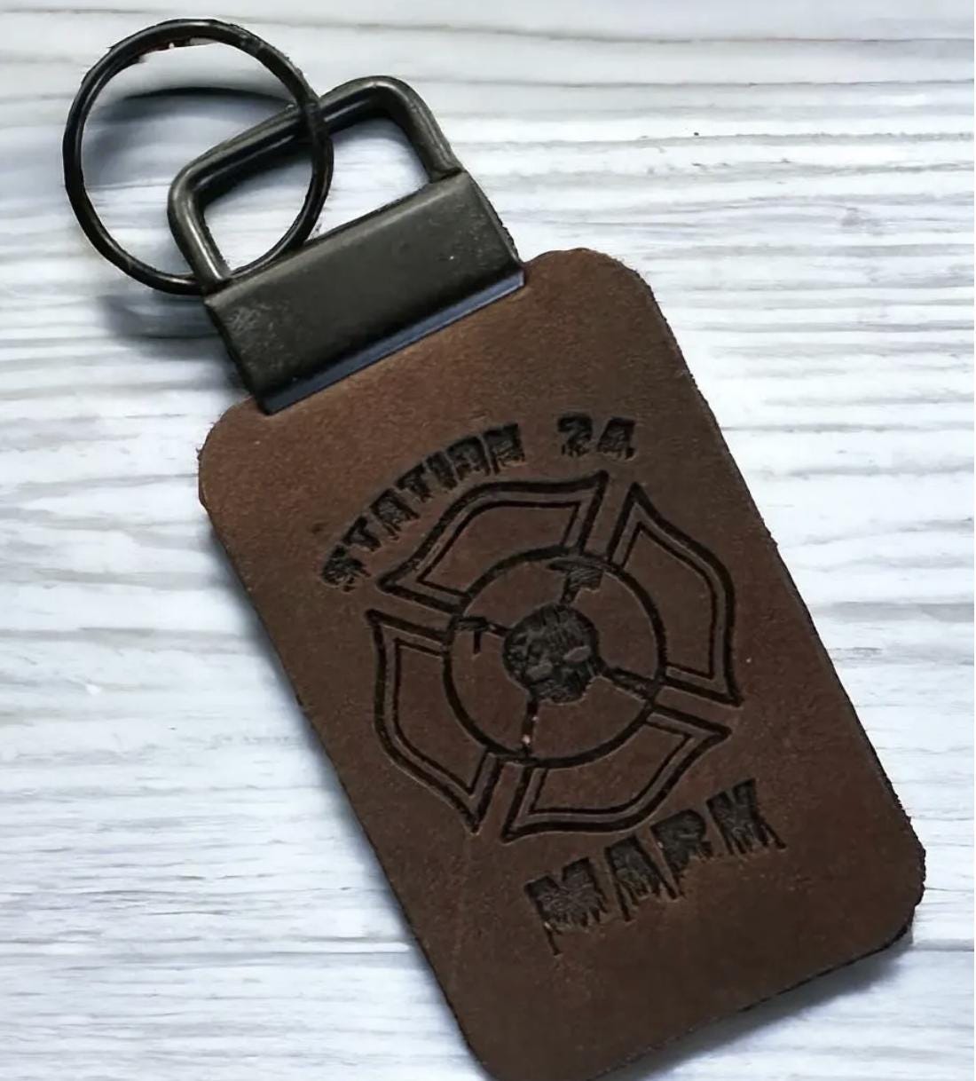 Leather firefighter keychain featuring engraved Maltese cross and skull emblem, handcrafted from full grain leather with optional custom name or station.

