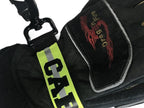 Close up of Personalized firefighter webbing glove strap with yellow reflective name, heavy-duty hardware, and structural firefighting gloves.
