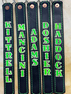 Handcrafted glow-in-the-dark leather SCBA quick release pulls displayed with personalized firefighter names on premium black leather.