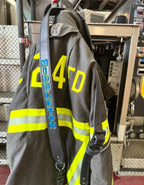 Custom leather firefighter radio strap hanging on firefighter turnout coat